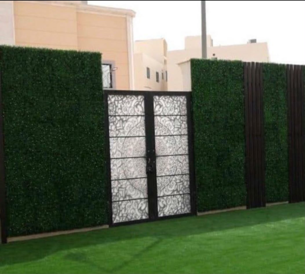 تنسيق جدار حديقة بخضار صناعية وبوابة